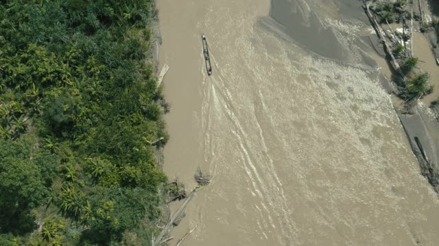 俯视图，跟随一个木制独木舟驾驶过一条大河与一个棕色的颜色在热带森林视频素材