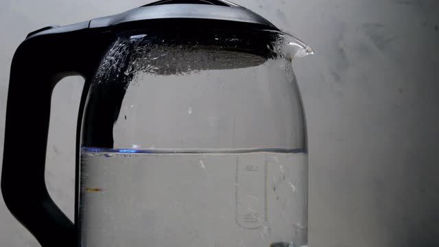 在透明的玻璃电水壶中沸腾的水和气泡视频素材