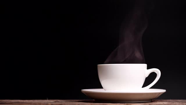 咖啡杯用天然蒸汽烟熏的咖啡在深色的背景与复制空间，慢动作。热咖啡饮品概念视频素材