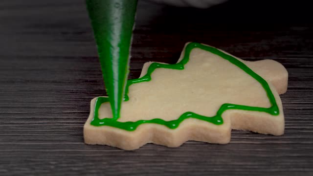 近距离绘制圣诞树糖饼干在木制桌子的背景与糖霜。视频素材