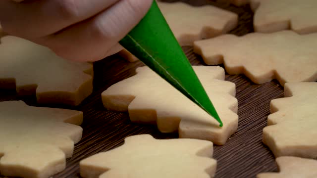近距离绘制圣诞树糖饼干在木制桌子的背景与糖霜。视频素材