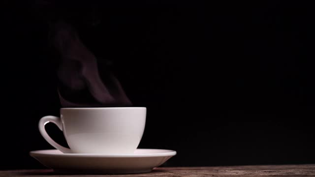 近距离的咖啡杯与自然蒸汽烟咖啡在黑暗的背景与复制空间，慢动作。热咖啡饮品概念。视频素材