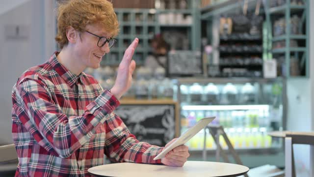 小红发男在咖啡馆用平板电脑在线视频聊天视频素材