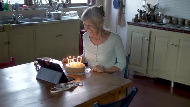 老祖母在视频通话中吹生日蛋糕蜡烛视频素材