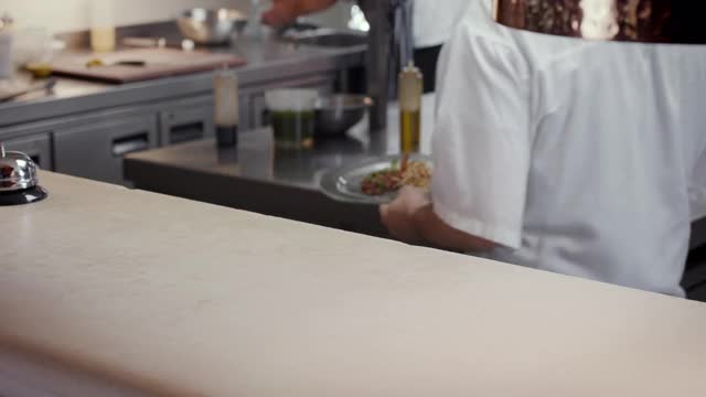 厨师将两道主菜放在柜台上让服务员端上视频素材