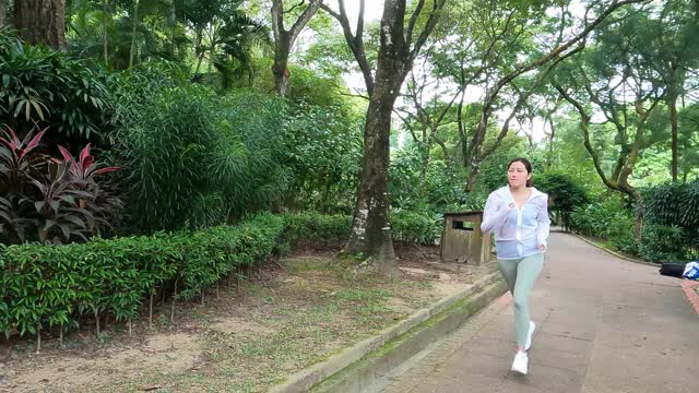 周末早上在公园里跑步的亚洲华裔年轻女子视频素材