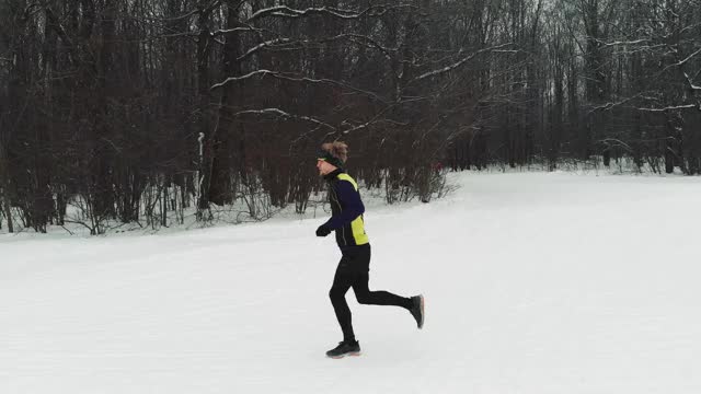 穿着运动服的跑步者在铁人三项前锻炼。冬季运动的概念。空中视频下载