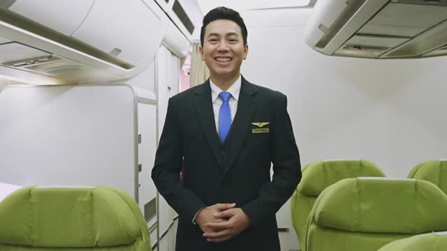 肖像亚洲男子空乘在经济舱微笑欢迎乘客视频素材