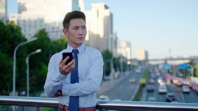 年轻商人在户外使用智能手机，4K视频购买