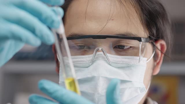 亚洲人在实验室试管中寻找化学反应视频下载