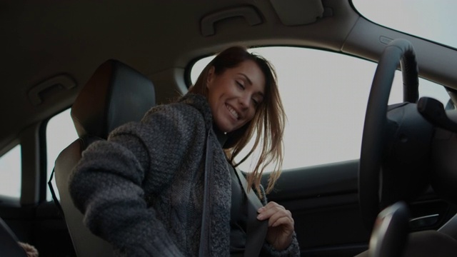 微笑的年轻女子坐在车里，系上安全带视频下载
