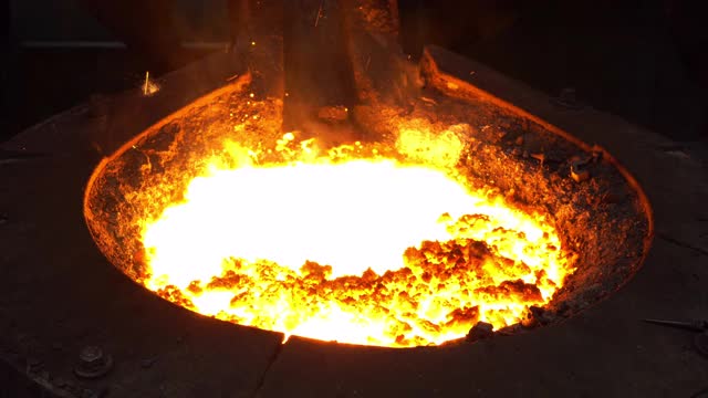 在铸造厂，操作人员将熔化的金属从熔炉中挤出，然后浇注到钢包中视频下载