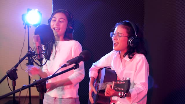 年轻的声学女性歌手录音音乐与吉他在工作室，录音室的概念视频素材