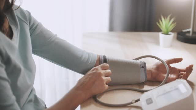 亚洲妇女用数字血压仪测量自己的血压视频下载