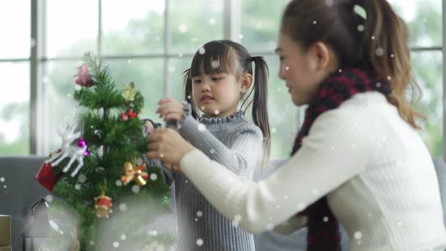 微笑的母亲和女儿在客厅装饰圣诞树视频素材