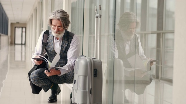穿着西装的成熟商人在机场候机楼里看书视频素材