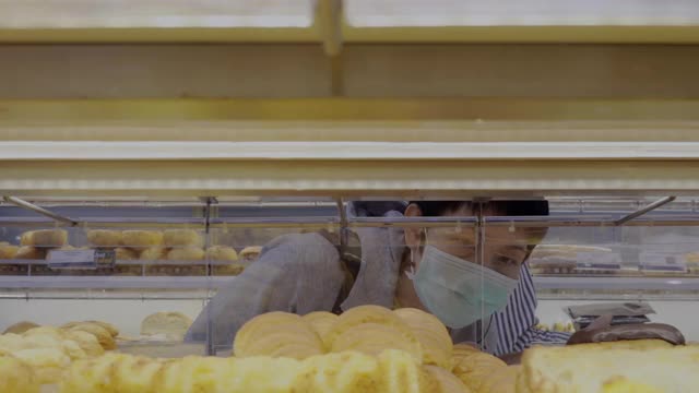 一位女士戴着口罩在面包店购物视频素材