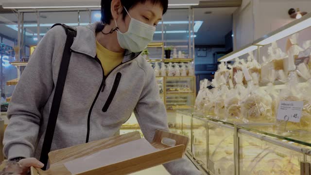 一位女士戴着口罩在面包店购物视频素材