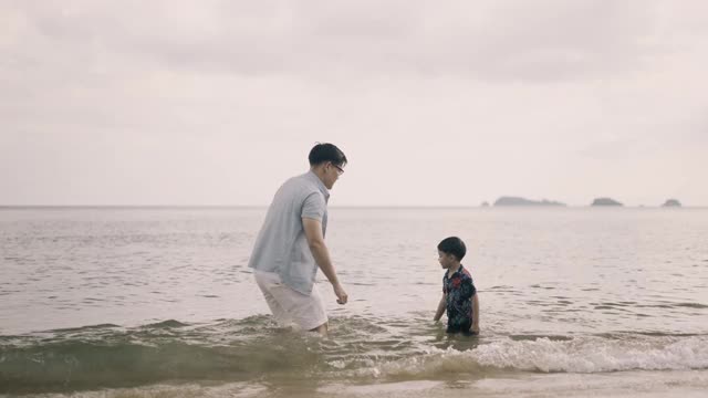 爸爸和儿子在海滩上玩海水视频素材