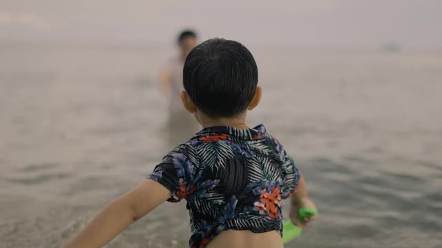 一个男孩在海水中向他的父亲走去视频素材