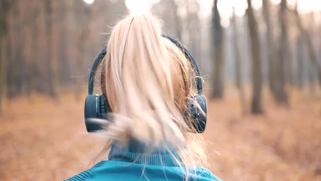 在森林里慢跑时戴着耳机的女人视频素材