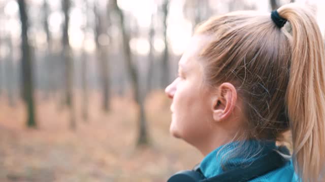 SLO MO女人戴着耳机走在秋天的森林里视频素材