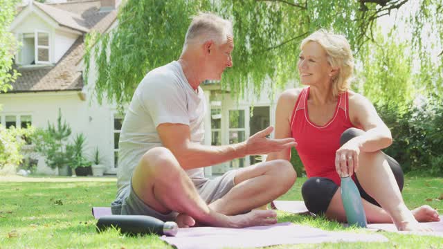 户外瑜伽课后，一对老年夫妇穿着健身服在家花园放松视频素材