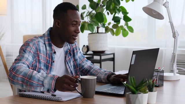 非裔美国商人一边用笔记本电脑工作一边喝咖啡视频素材