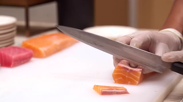 4K高清慢镜头手持:拉近厨师的手切生鲑鱼和金枪鱼，作为生鱼片，日本groumet美食。视频下载