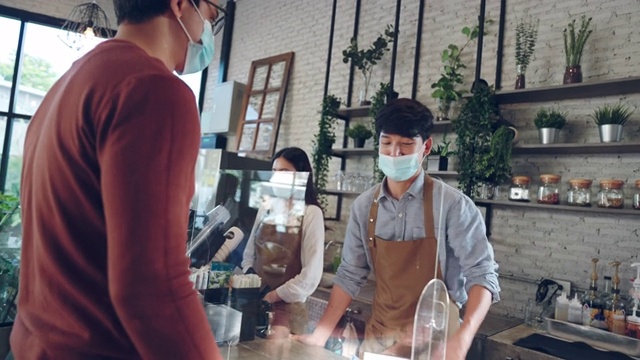 亚洲顾客戴着防护面具在咖啡馆排队等候付款和买咖啡视频下载