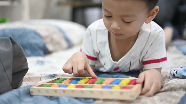 学龄前的小男孩学会数数。可爱的孩子玩珠算玩具。小男孩在家里玩。视频下载