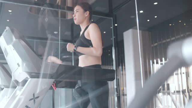 在跑步机上跑步的女人，新常态和现代健身房视频素材