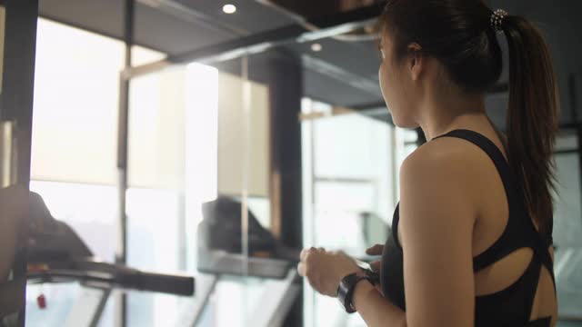 在跑步机上跑步的女人，新常态和现代健身房视频素材