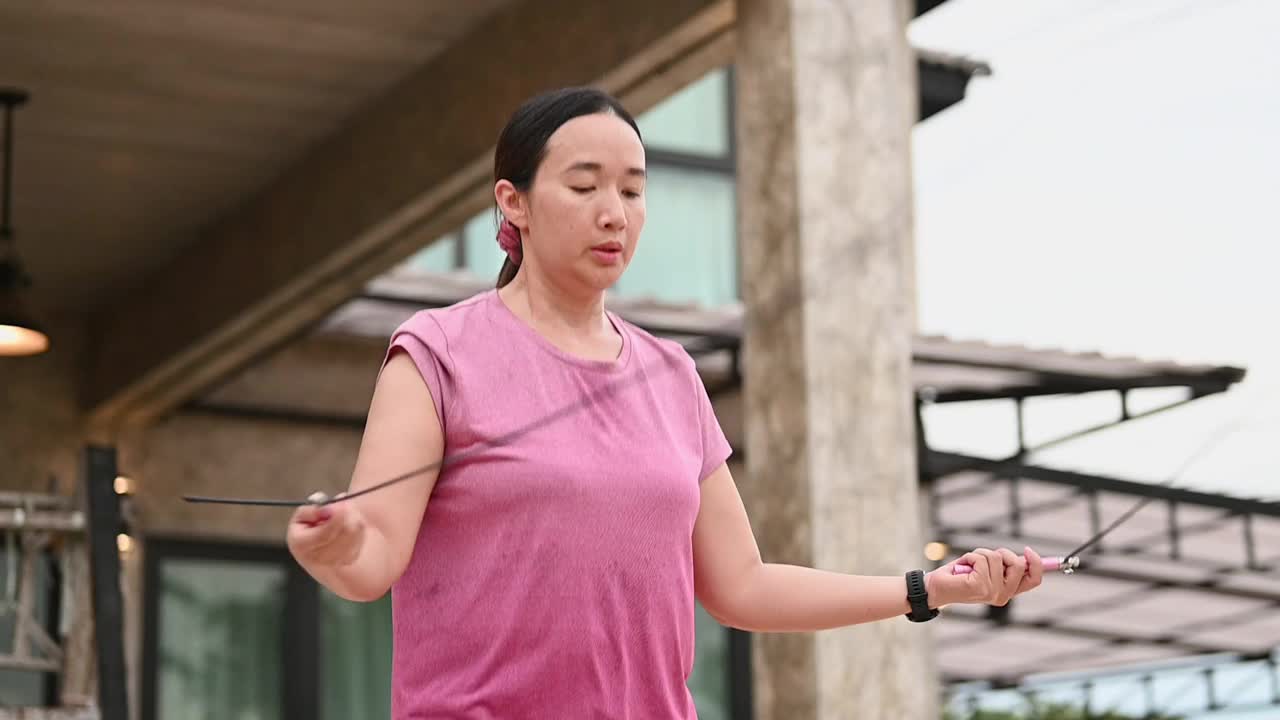 亚洲女孩在人行道上跳长袍，生活方式概念，亚洲女人在家里锻炼，有吸引力的女性在她的前面的家做运动。她在做运动。视频下载