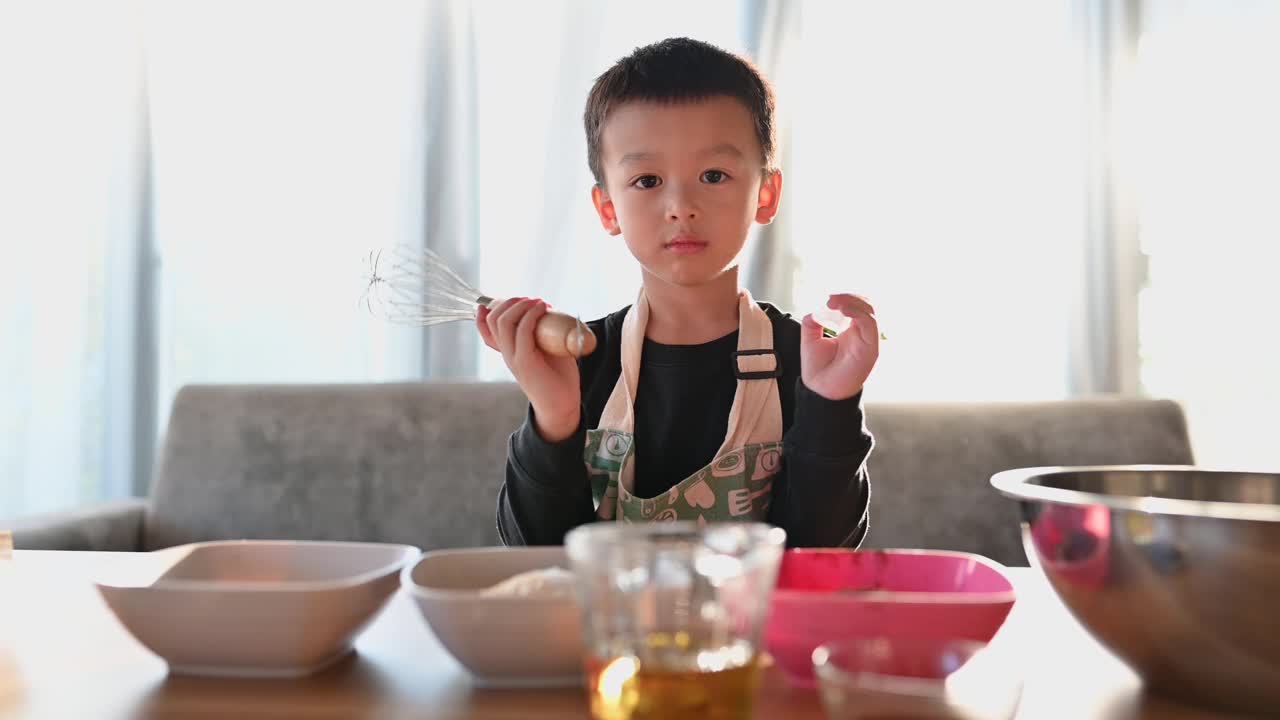 亚洲快乐可爱的男孩准备设备，帮助他的母亲做蛋糕。家庭活动的概念。视频下载