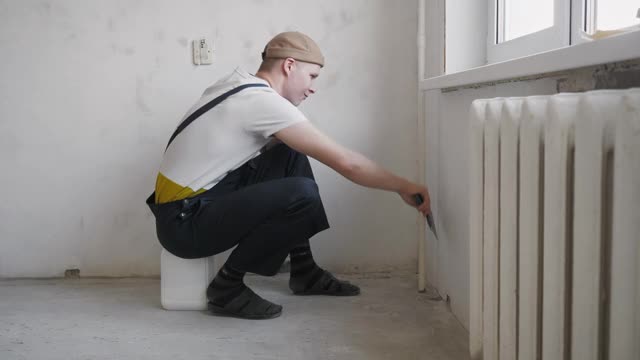 一个男人在涂完油灰后用抹刀擦墙视频素材