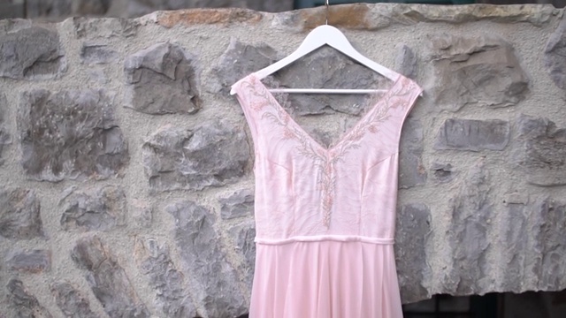 一件淡粉色的串珠胸衣挂在石墙上，特写视频下载