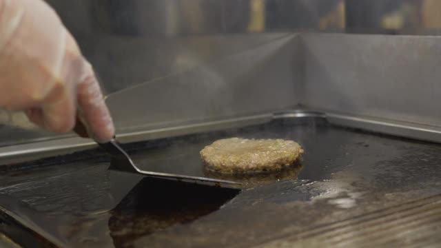 关闭了。制作奶酪汉堡。厨师将炸过的牛肉片放在烤架上，放上双层芝士，准备将汉堡放在烟熏烤架上。视频素材