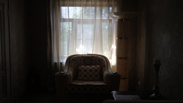 黑暗的室内，老式扶手椅的背景是一扇带窗帘的窗户视频素材