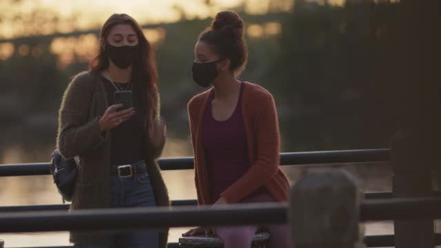 两个戴着防护面罩的女性朋友在河边户外自拍视频素材