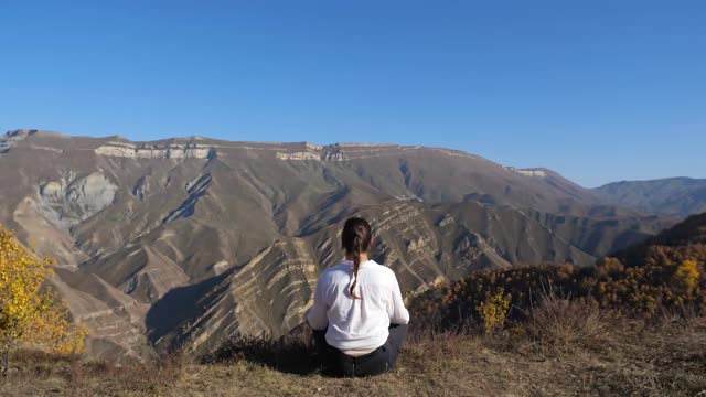 一个女人坐在大山边上沉思视频素材