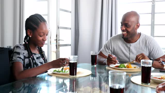 非洲黑人家庭在一起吃午饭。父亲和女儿在吃饭视频素材