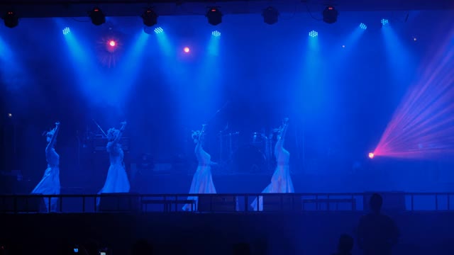 一群身穿白裙的舞者在聚光灯或迪斯科灯光下在舞台上表演视频下载