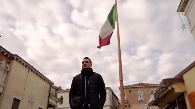 一名男子背着意大利国旗走在城市街道上视频下载