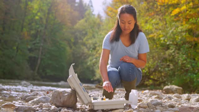 亚洲女性生物学家从河里取水样并做pH值测试视频下载