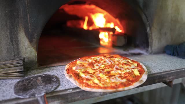 4K披萨在传统砖披萨烤箱。厨师在厨房用肉、奶酪和蔬菜制作披萨面团，为意大利餐厅的顾客服务。意大利食物和餐厅的概念视频素材