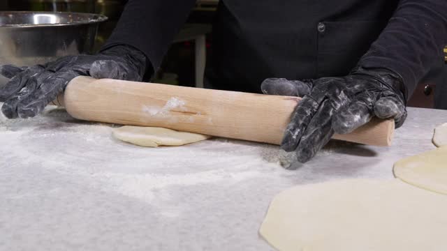 手在黑手套面包店厨师在面团上应用面粉的特写镜头，孤立的背景4k镜头。2020年流感大流行期间在家做饭呆在家里的概念。视频素材
