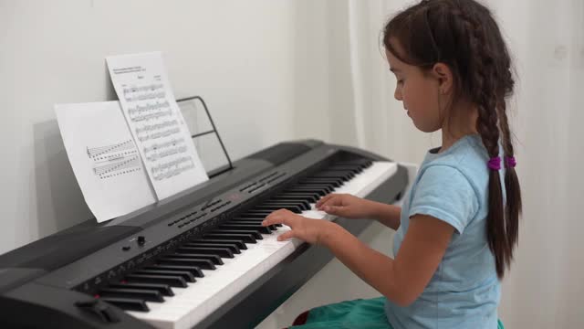 小女孩对着钢琴键盘微笑视频素材