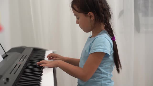 小女孩对着钢琴键盘微笑视频素材