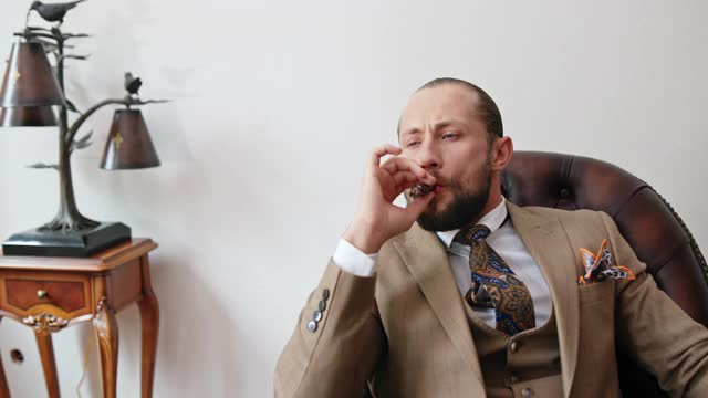 穿着昂贵西装的实心富翁坐在办公室的一张木桌前抽烟视频素材
